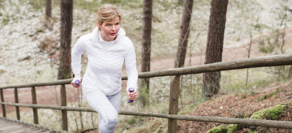 Træning kan være mere effektivt end medicin - på billedet er en kvinder i løb op af en lang trappe ude i naturen med håndvægte i hånden